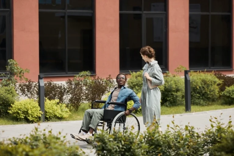 Disabled man in wheelchair outside with support worker